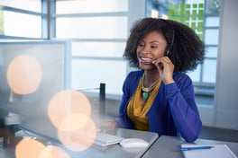 Portrait of a smiling customer service representative with an afro at the computer using headset.jpeg