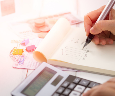 Hands with a calculator typing in numbers and writing down the answers to symbolize financial calculation for higher margins